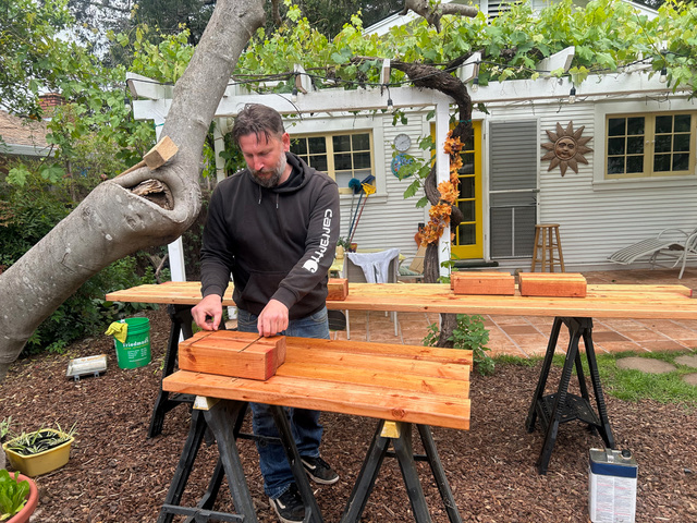 Co-op worker applying protective sealer to freshly cut cedar boards
